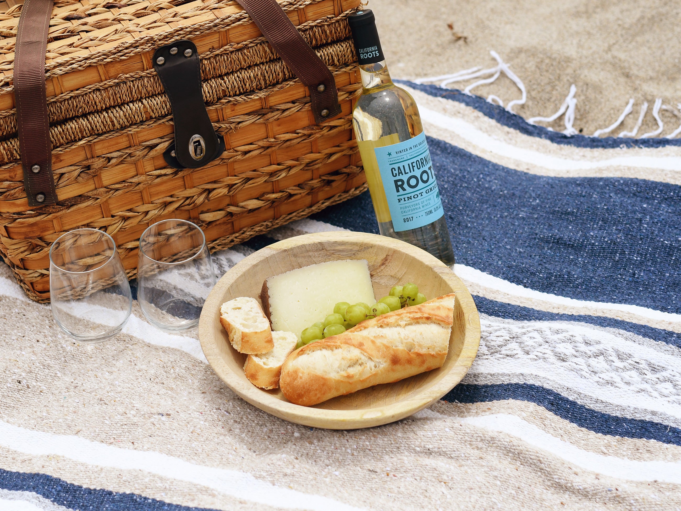 A photo of a Mexican Blanket laid out with a picnic basket and wine bottle.