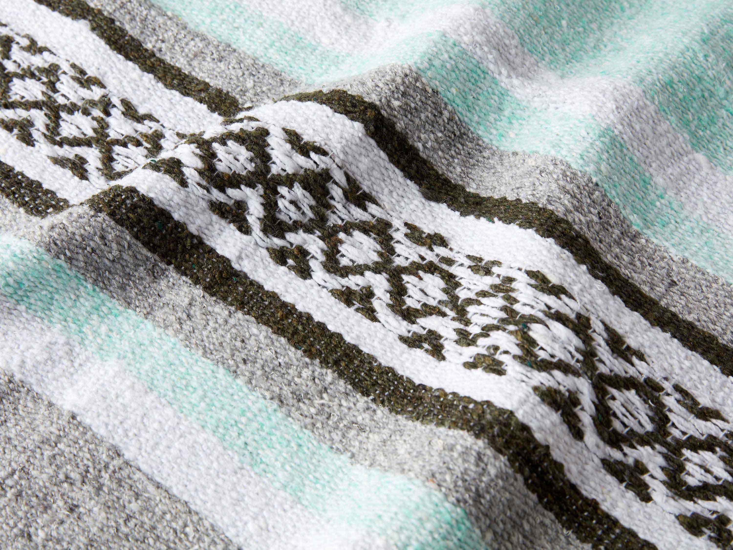 A close up shot of a mint and gray patterned Mexican Blanket