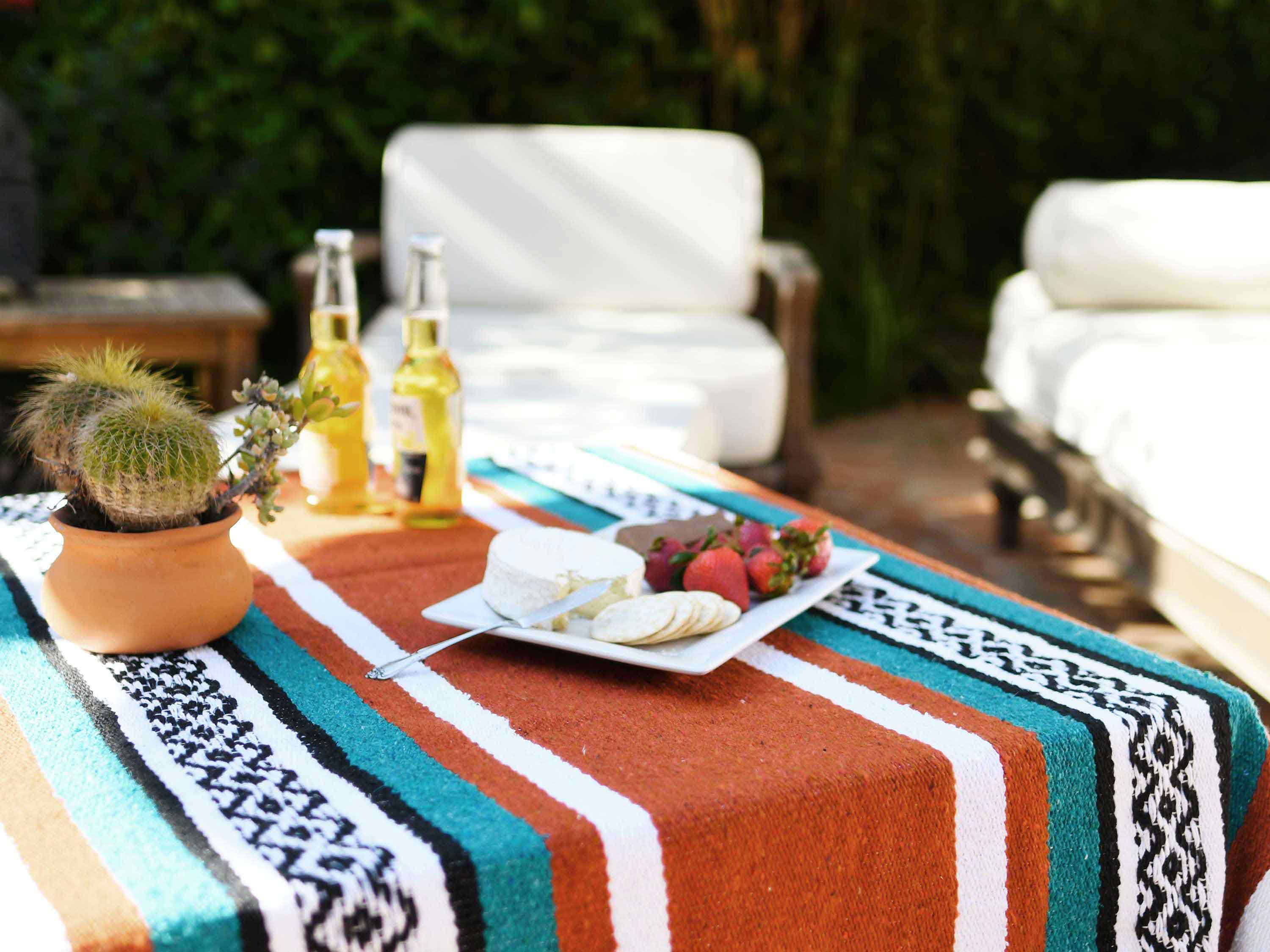 A Mexican blanket draped over a table with a picnic set.