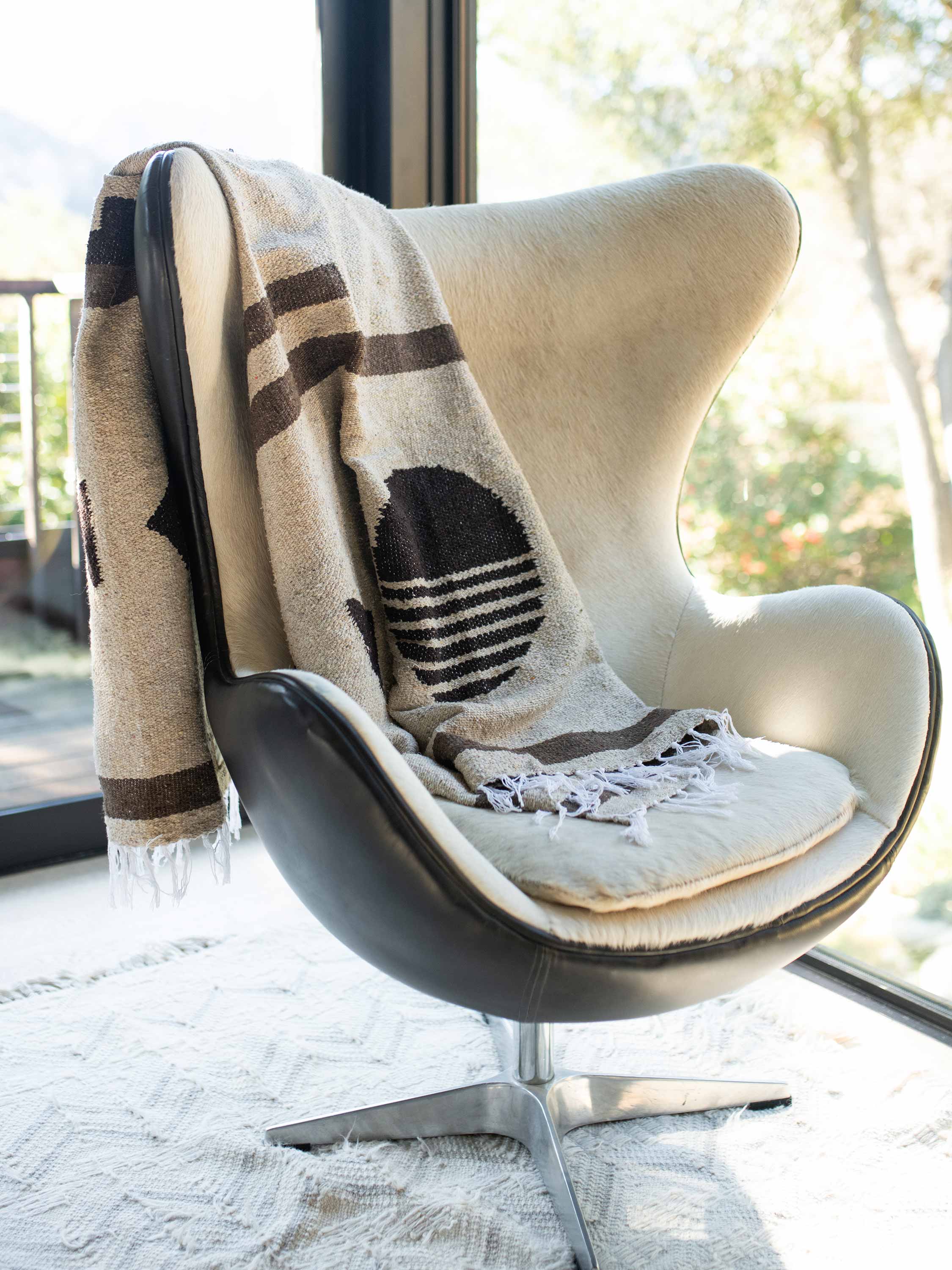 A cream and brown colored Mexican Blanket draped over a chair.