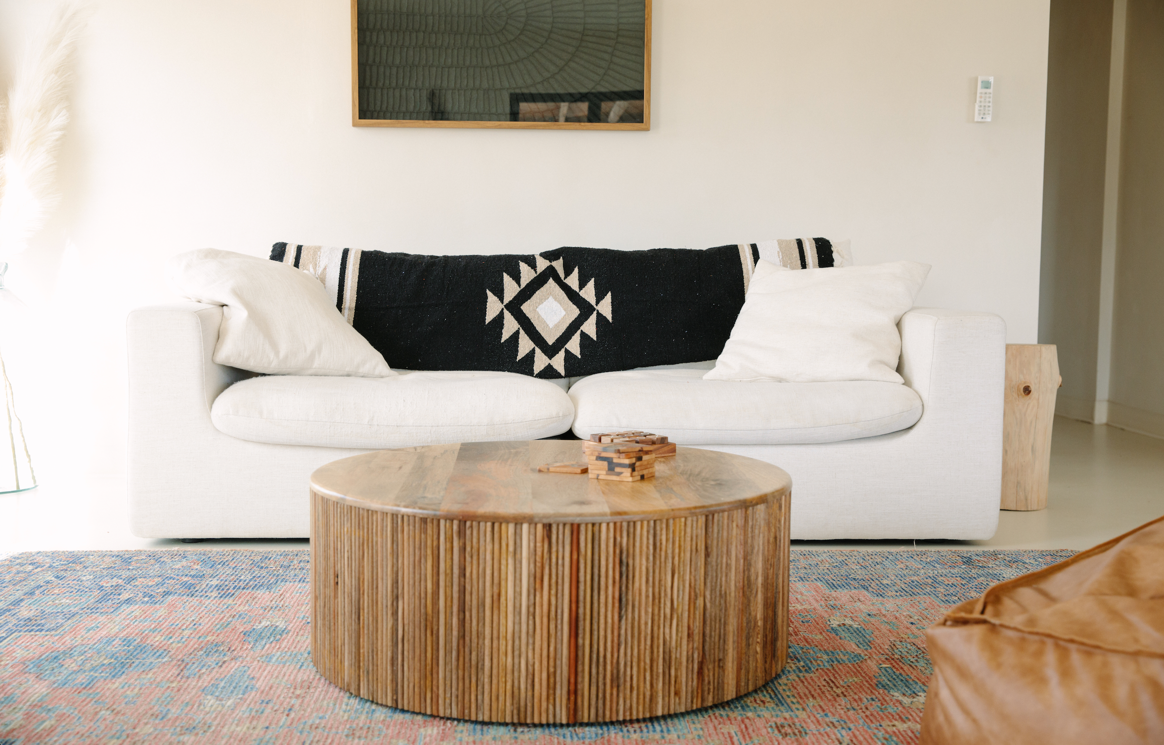 A black Mexican blanket draped over a cream colored couch.