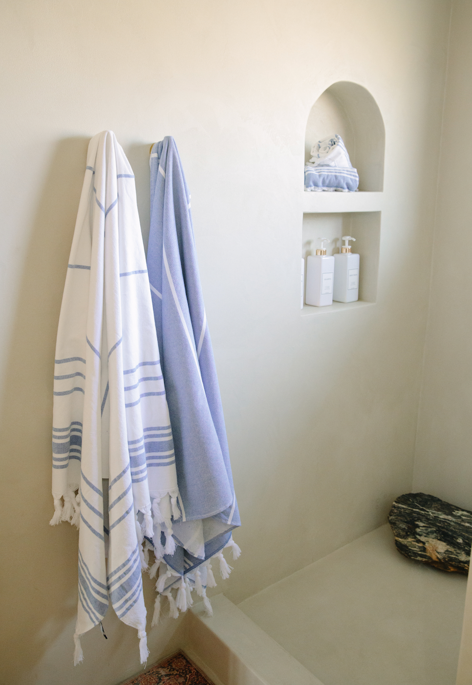 A pair of Turkish Towels hanging on the wall of a bathroom.