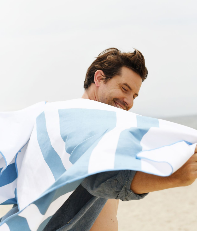 A man draped in a blue striped microfiber towel.