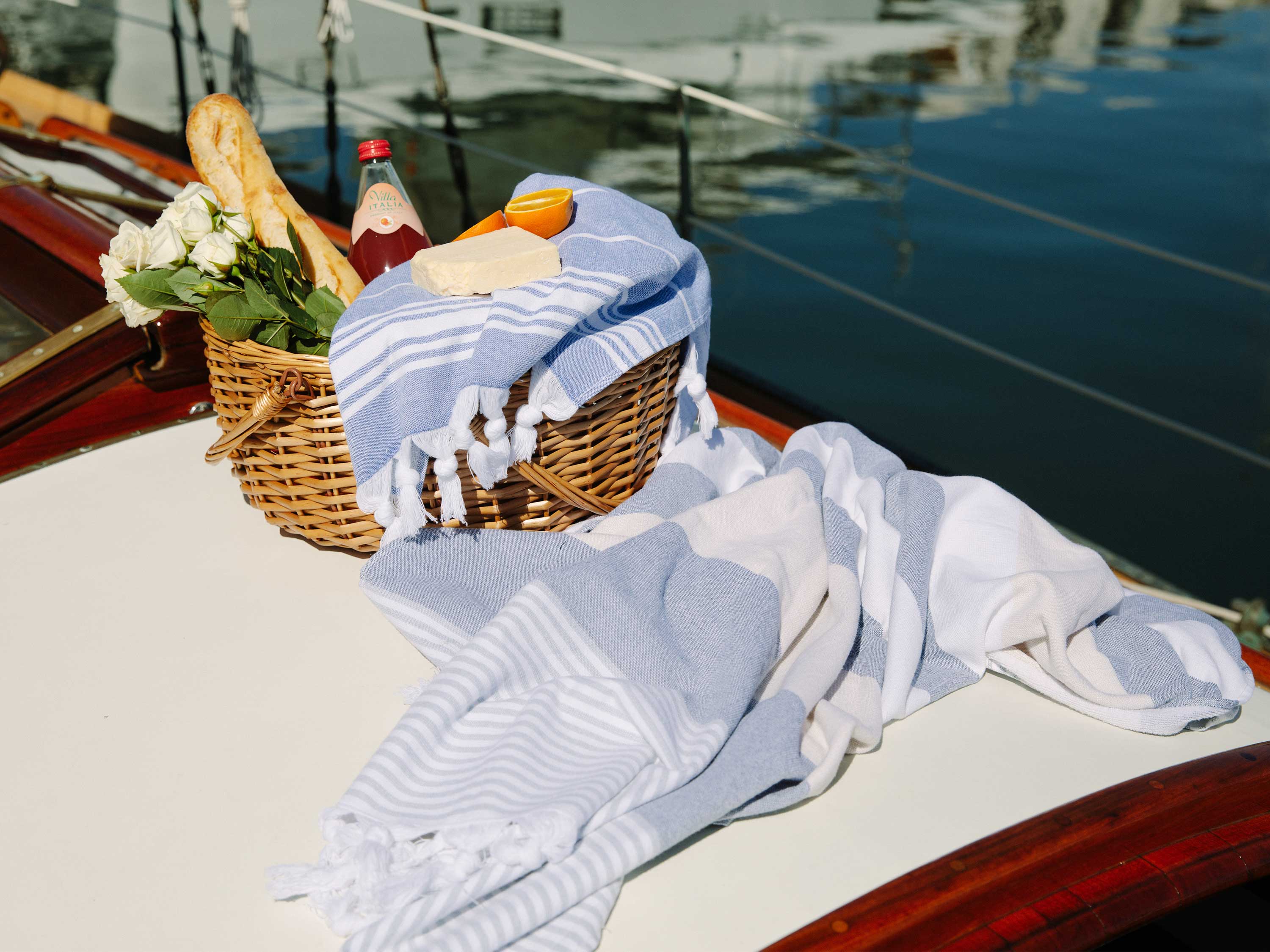 A picnic basket with a blue Turkish Towel draped over it.