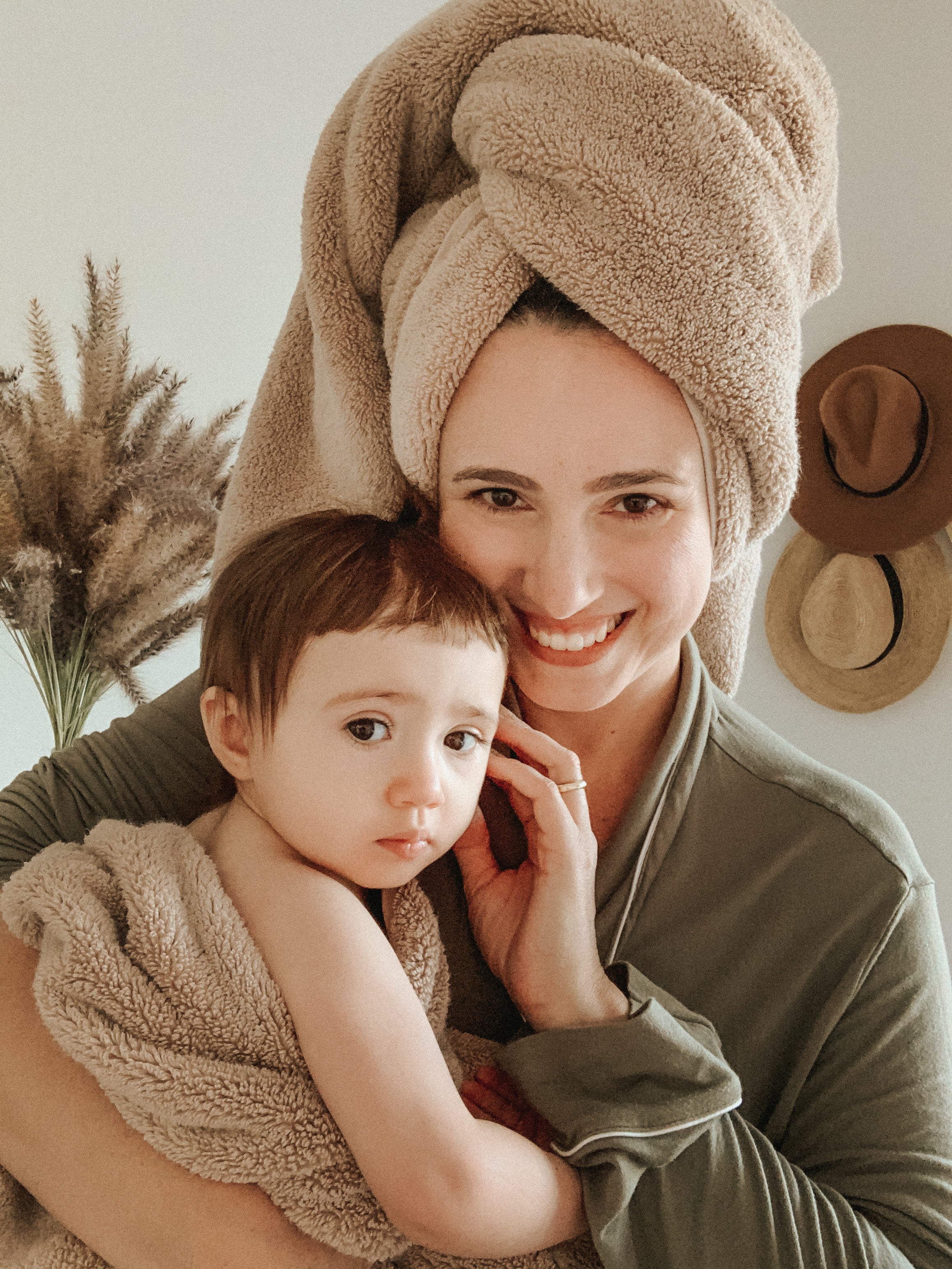 A woman hugging a child wrapped in a tan bath towel.