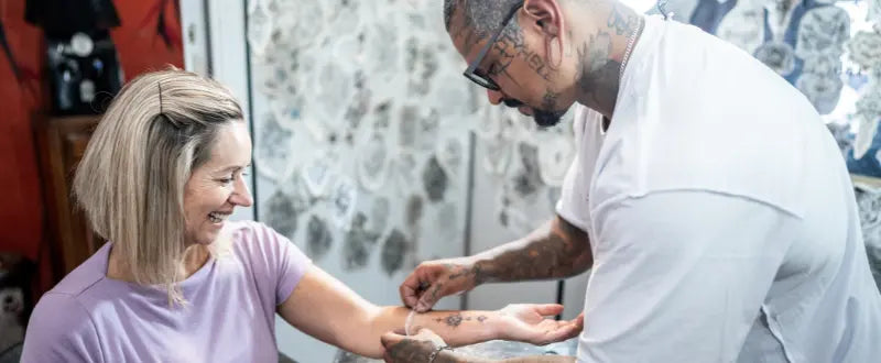 Tattoo artist covering woman's tattoo with plastic film