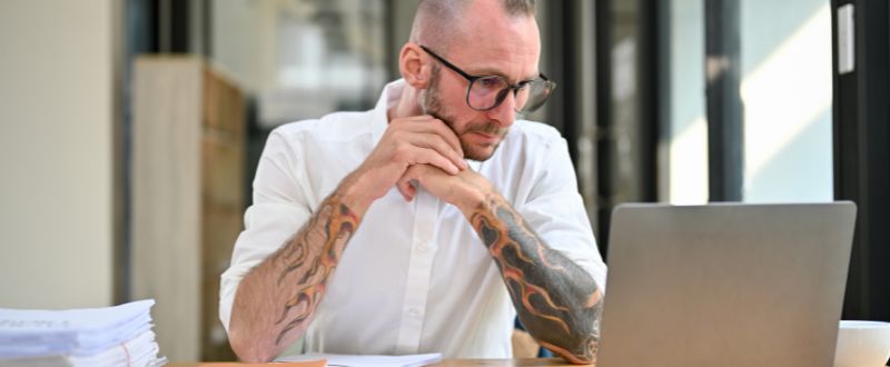 a businessman with tattoos looking his laptop