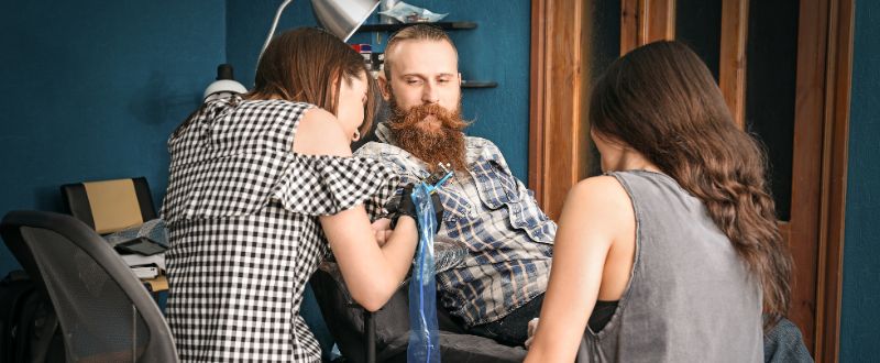 a tattoo apprentice watching the tattoo artist