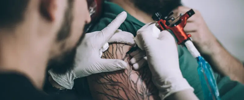 a tattoo artist tattooing his clients