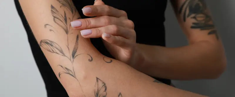 a woman applying cream on her arm tattoo