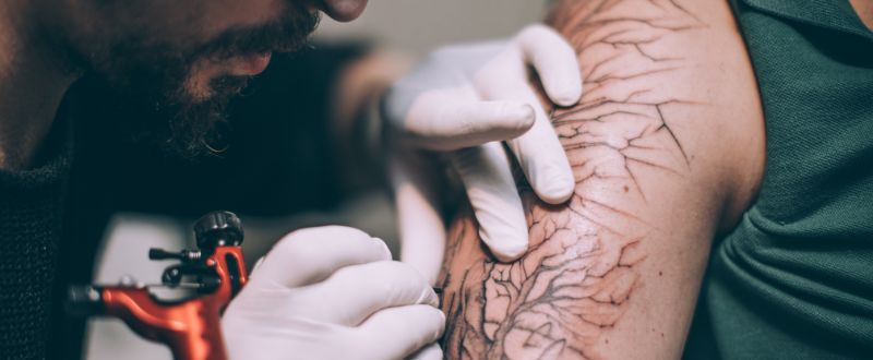 an artist doing a tattoo on his client