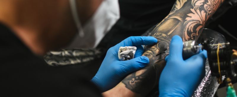 an artist tattooing a hand tattoo