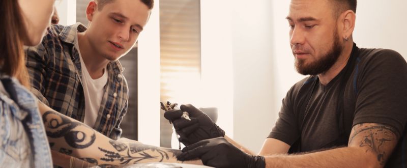 an artist tattooing his clients