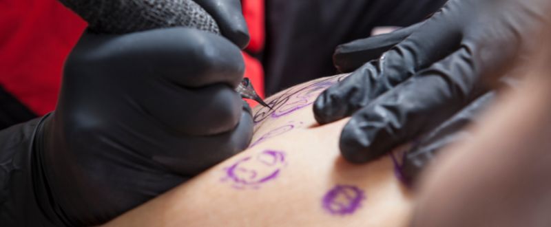 artist making a tattoo outline with machine