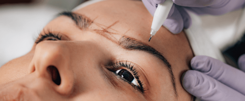 Beautician doing permanent brow tattoo