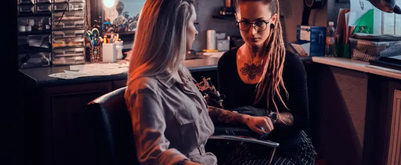 female tattoo artist tattooing her client