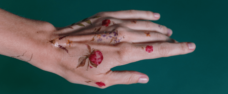Delicate flower tattoos on a woman's hand