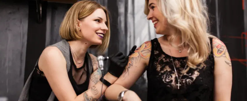 happy tattoo artist and her client