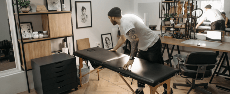 Man setting up tattoo furniture while opening up a tattoo shop