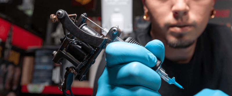 Tattoo artist holding machine with needle