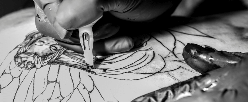 Tattoo artist adding shading to his black and grey design