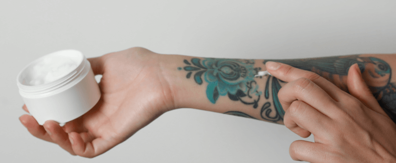 Woman rubbing tattoo cream into arm