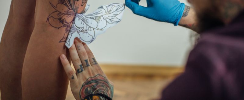 tattoo artist putting a tattoo stencil