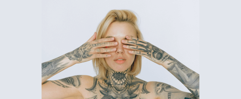 Tattooed woman covering eyes