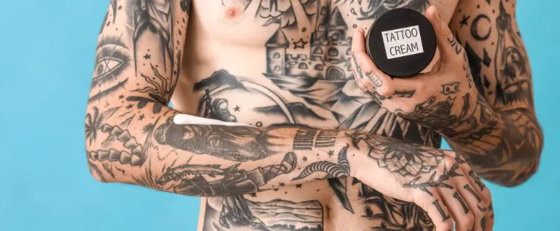 tattooed body holding a tattoo cream