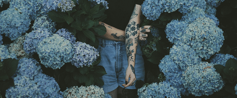 Woman with rose tattoo among blue flowers