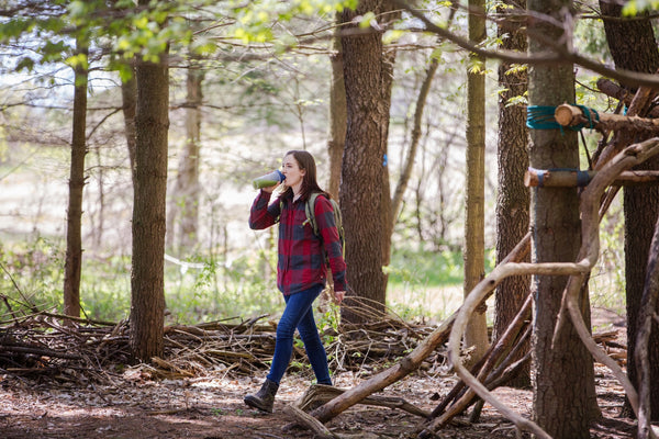 Woman walking while drinking matcha in the woods