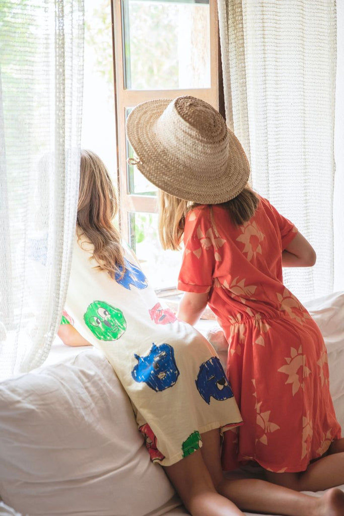 Little girls looking out window in Fresh Dinosaurs Sun Dress at Design Life Kids