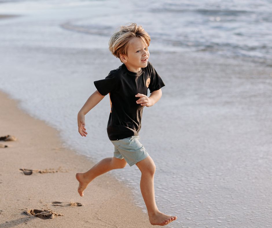 Young boy running on the beach in Munsterkids Beachside Shorts at Design Life Kids