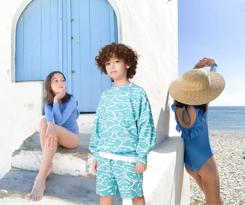 Young girl posing in Casa Blue Swim Palma Swimsuit and young boy in Molo Monti Waves Of Joy Sweatshirt and Adian Waves Of Joy Shorts at Design Life Kids