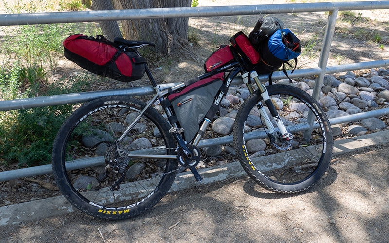 Brett’s loaded El Mariachi titanium mountain bike leans on a fence.