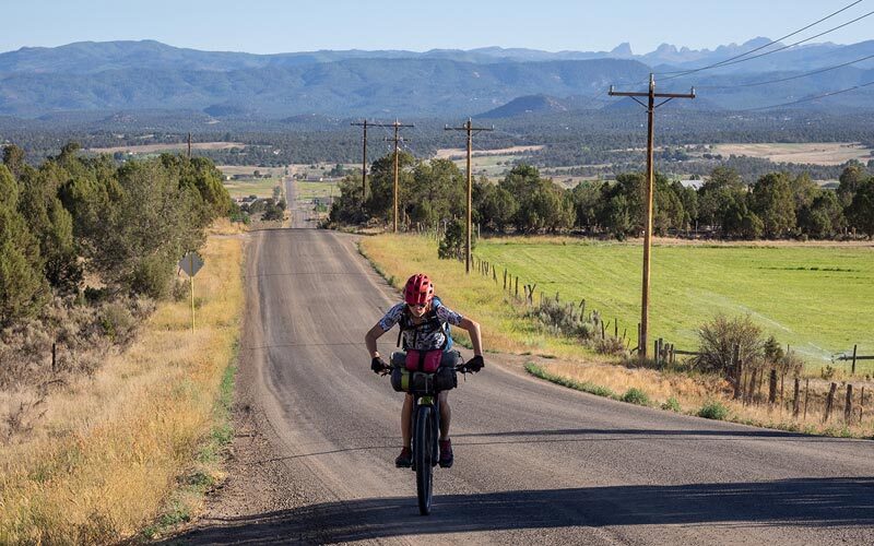 Diana pedals up an incline on a long gravel road through farm country, the hot sun beating down.