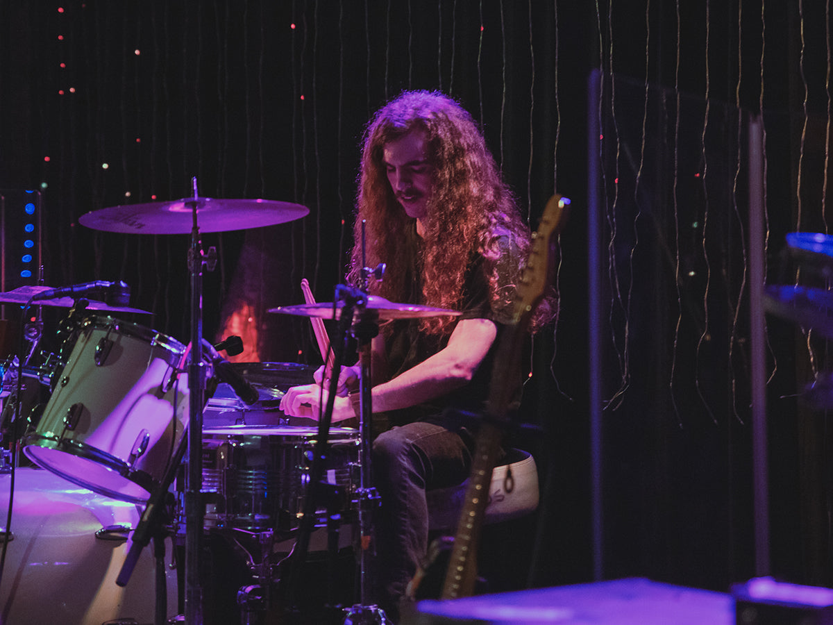 Drummer Zylar Ritzler poses with Scorpion Percussion drumsticks behind his drumkit