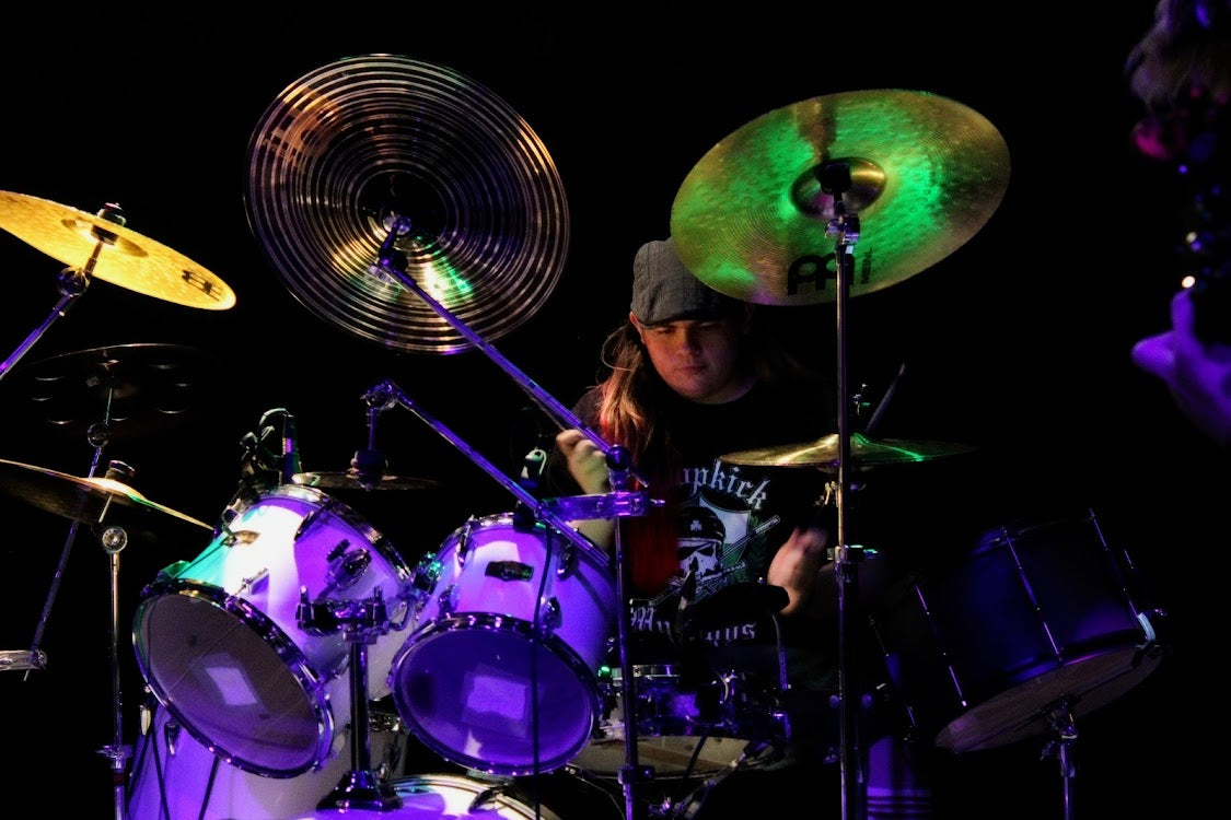 Drummer Jacoby Barnhill poses with Scorpion Percussion drumsticks behind his drumkit