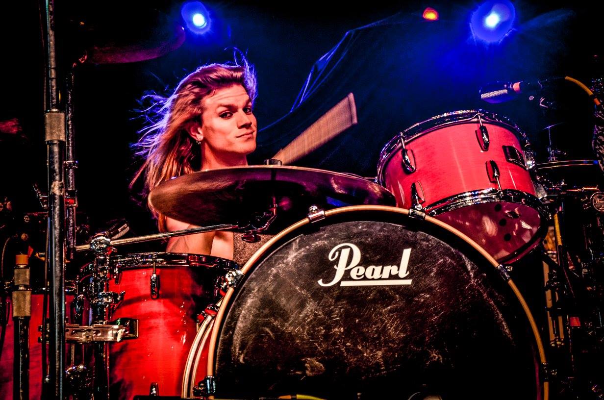 Drummer Drew Dye poses with Scorpion Percussion drumsticks behind his drumkit