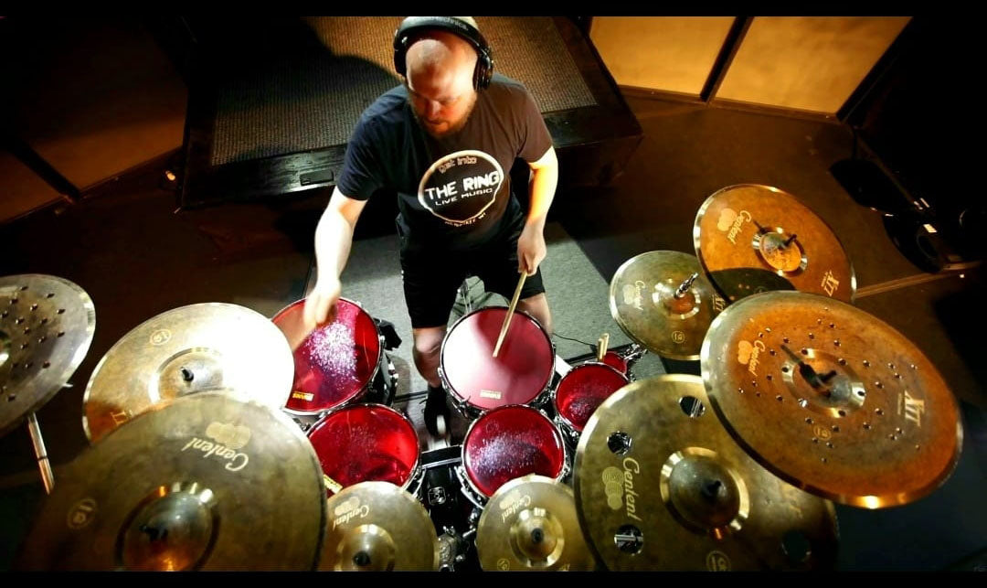 Drummer Chris Oelke poses with Scorpion Percussion drumsticks behind his drumkit