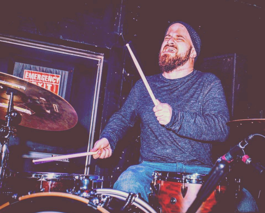 Drummer Samuel Gutsmiedl poses with Scorpion Percussion drumsticks behind his drumkit