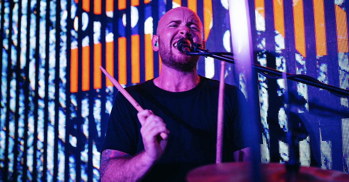 Drummer Ashton Dalfino poses with Scorpion Percussion drumsticks behind his drumkit