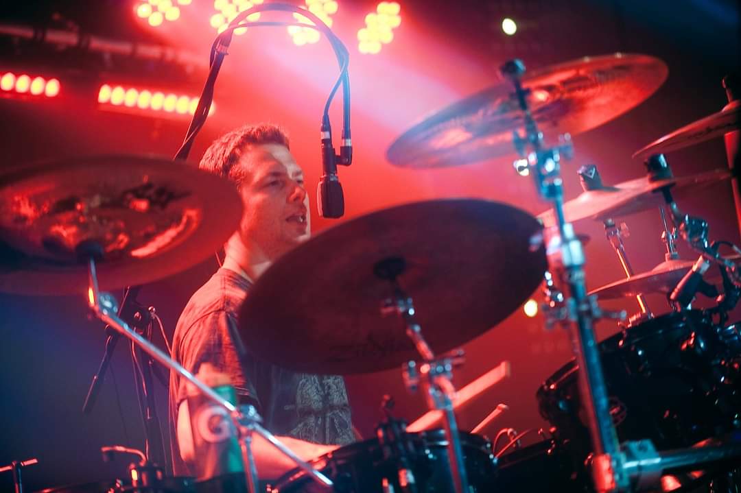 Drummer Chris James DiDomenico poses with Scorpion Percussion drumsticks behind his drumkit