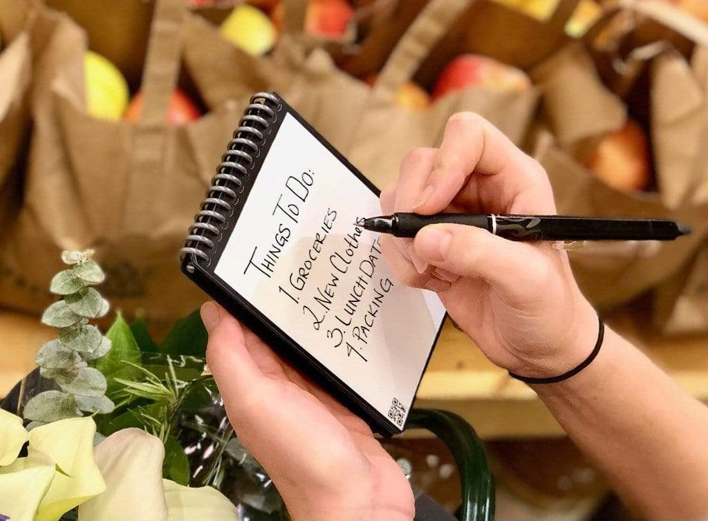 A person writing a to-do list with the Rocketbook Mini