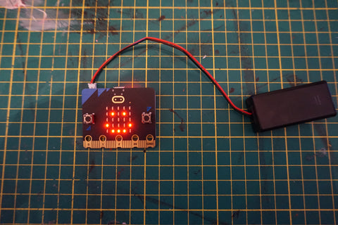 close up of the micro:bit board with the LEDs lit up to show a smiley face