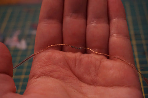 open hand holding two wires soldered together at the middle 