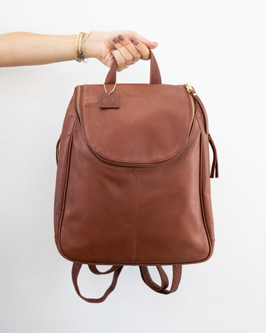 hand holding nora backpack in brandy