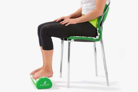 woman sitting on prosourcefit acupressure mat with feet on pillow