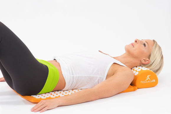 woman laying on orange prosourcefit acupressure mat and pillow set