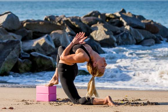 Woman doing yoga on beach with ProsourceFit pink foam yoga blacks